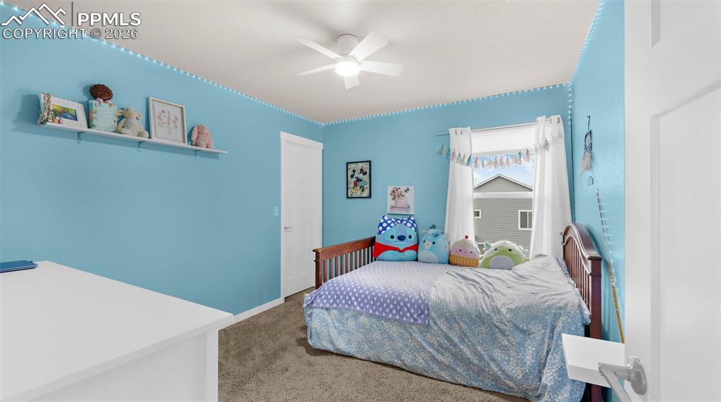 Carpeted bedroom featuring ceiling fan and baseboards