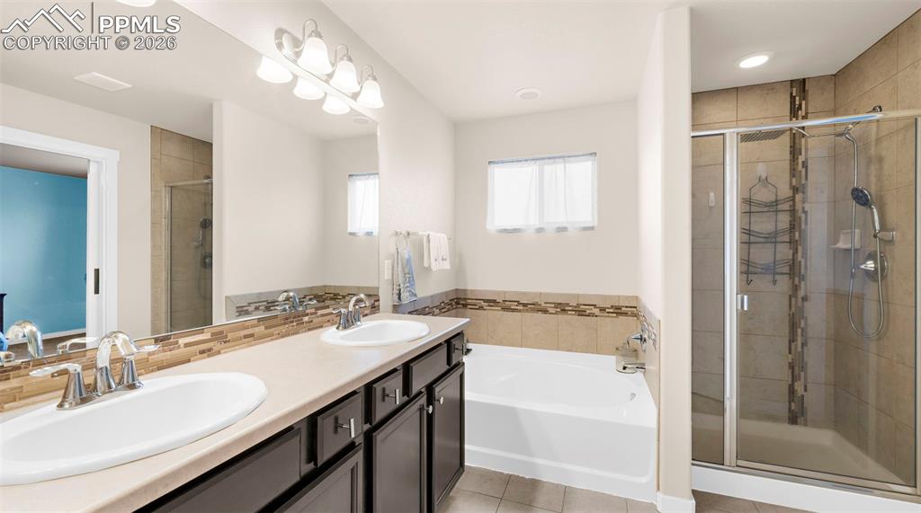 Bathroom with double vanity, a garden tub, a stall shower, and light tile patterned floors