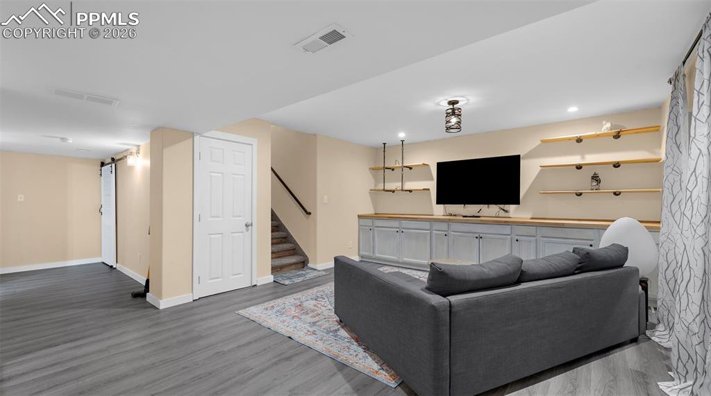 Living room with dark wood-type flooring, recessed lighting, and a barn door
