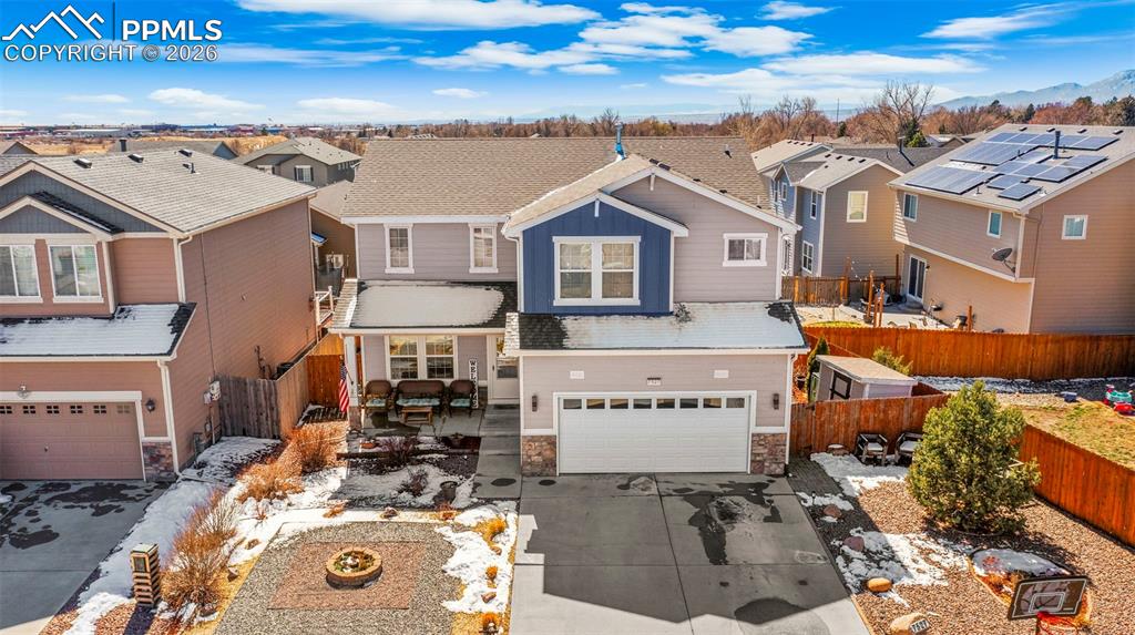 View of front facade featuring a residential view, stone siding, an attached garage, and concrete driveway