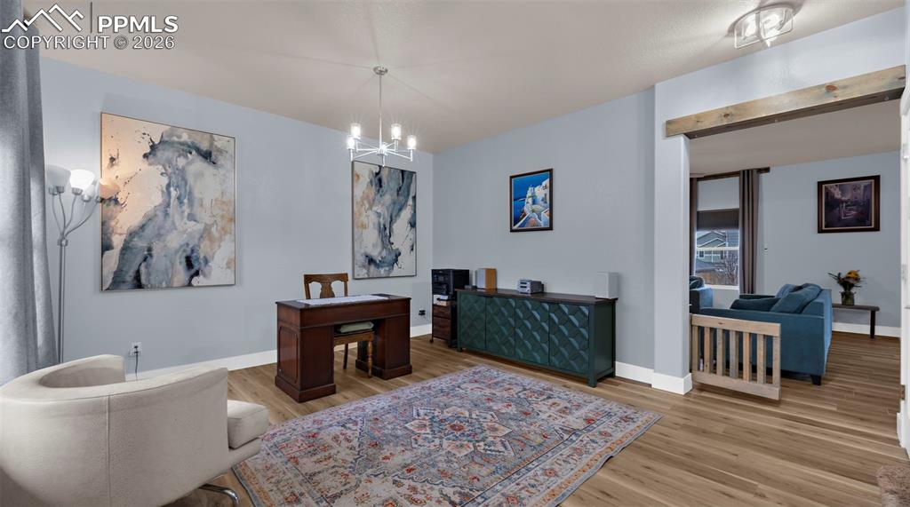 Dining space with light wood-style flooring, suspended lighting, and an office area