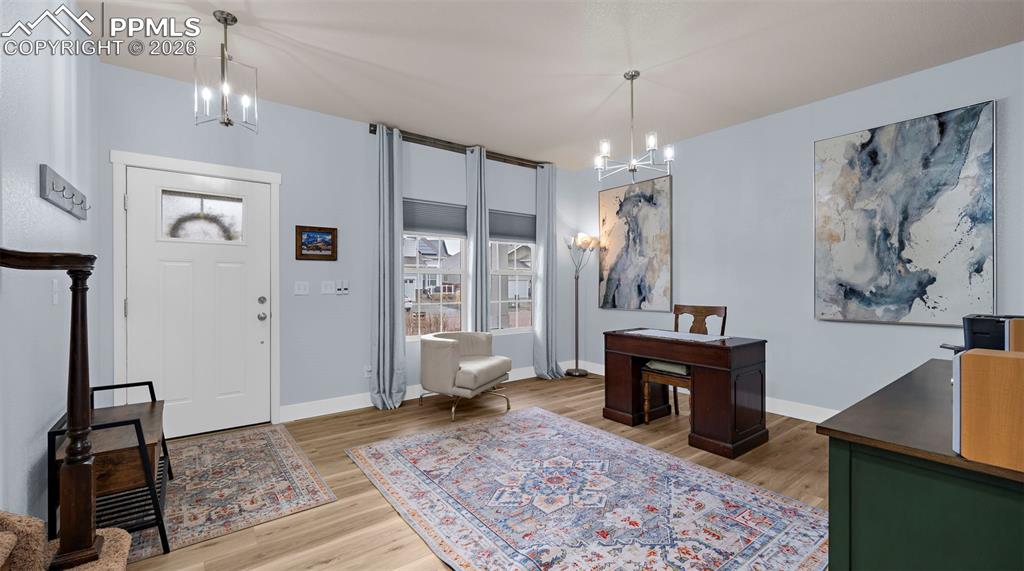 Foyer entrance featuring suspended lighting, light wood-style flooring, and healthy amount of natural light