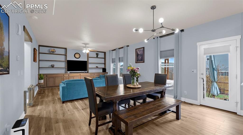 Dining area featuring light wood-style floors, suspended lighting, and a ceiling fan