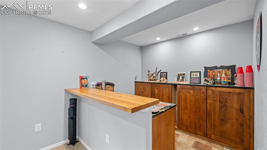 Indoor dry bar featuring butcher block countertops, wood finish cabinets, and recessed lighting