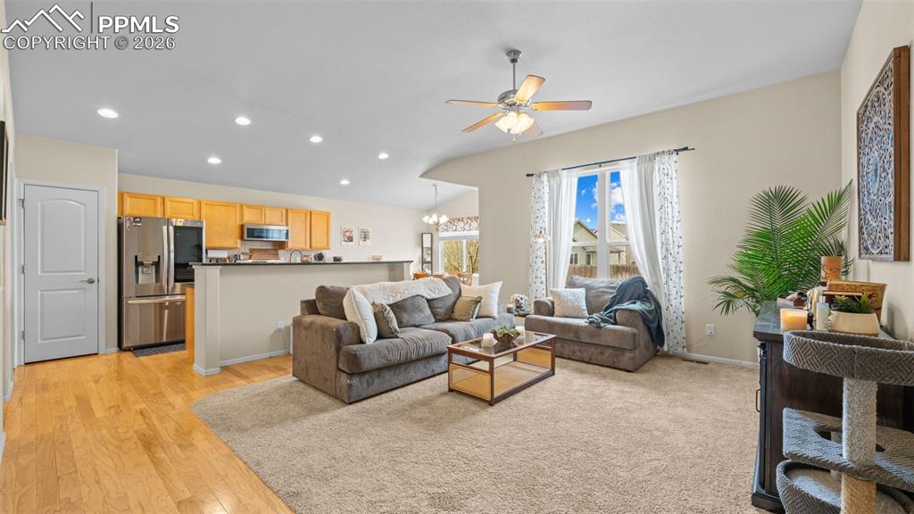 Living room featuring ceiling fan, light wood-style floors, and a chandelier