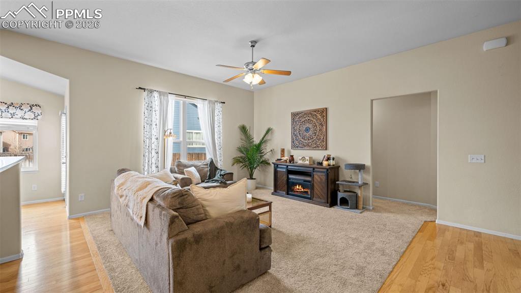 Living area featuring light wood-style floors, a ceiling fan, and a glass covered fireplace