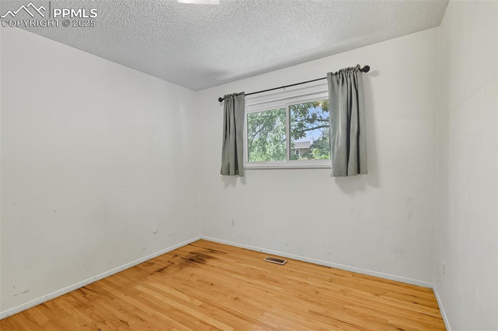 Upper spare room featuring wood finished floors and a textured ceiling