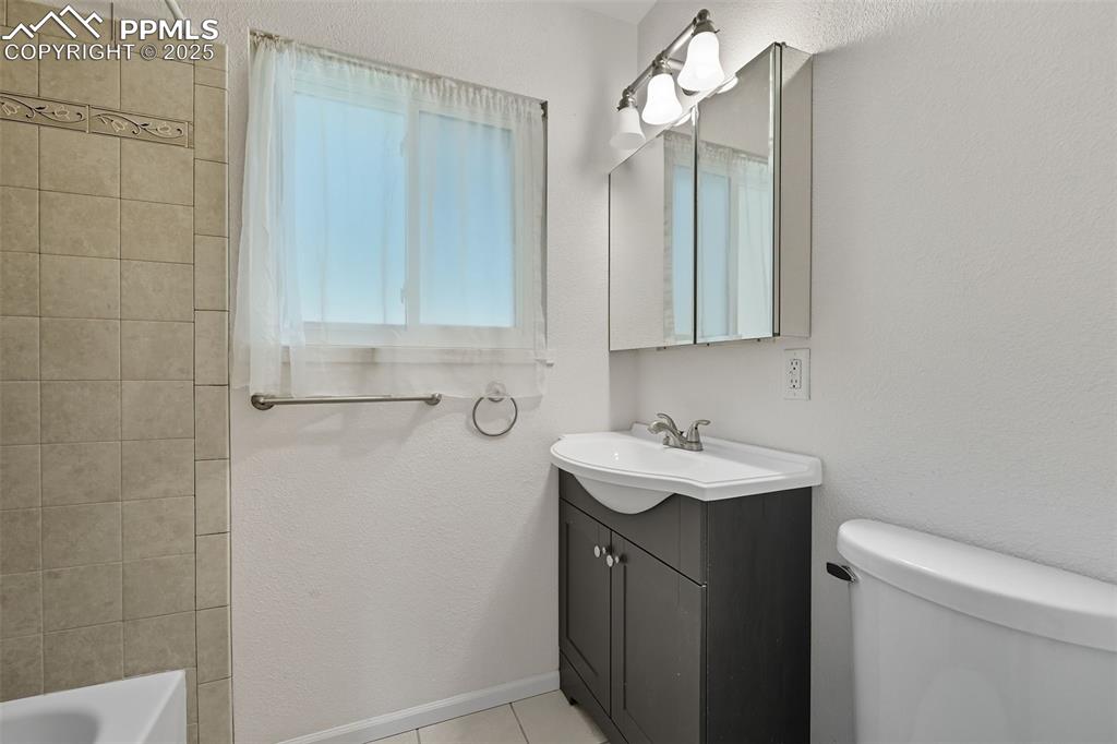 Upper bathroom with a textured wall, vanity, and light tile patterned floors