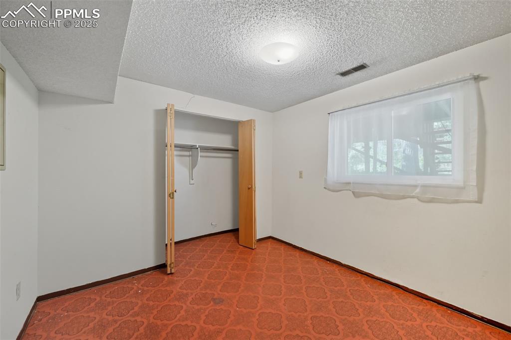 Lower bedroom 1 featuring a textured ceiling, a closet, and carpet floors