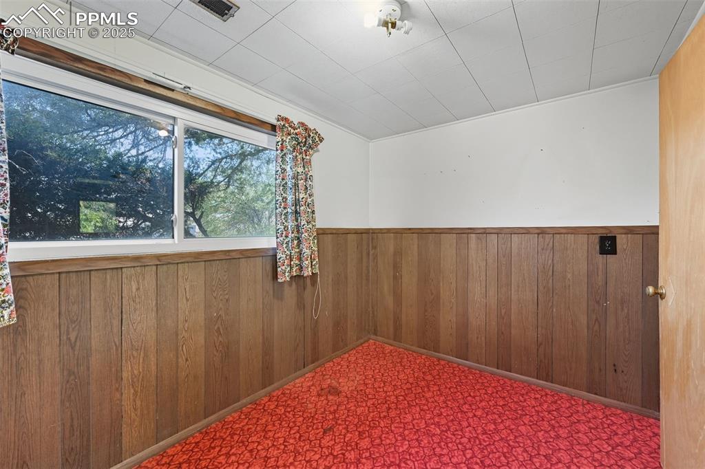 Lower bedroom 3 with wooden walls, wainscoting and walk in closet