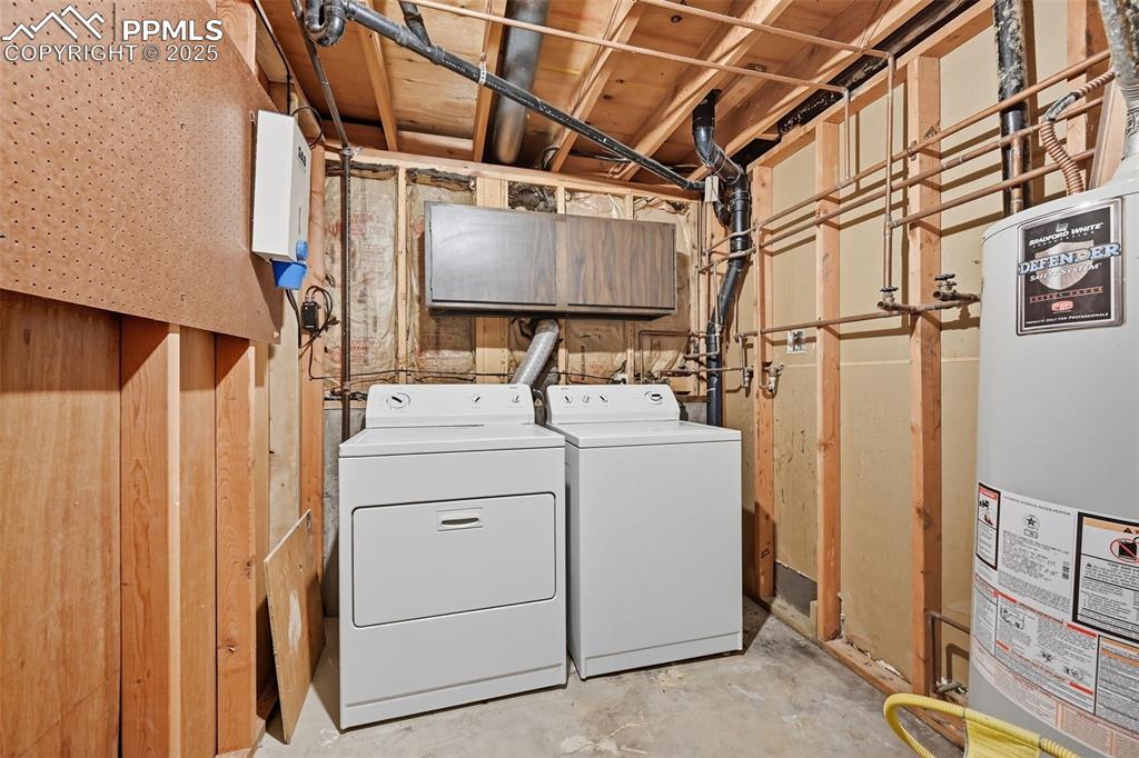 Laundry area featuring unfinished concrete flooring, gas water heater, and washer and clothes dryer