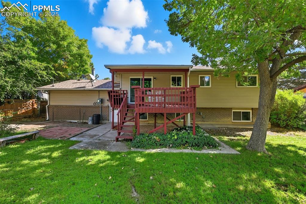 Back of house with a deck, brick siding, stairs, and a patio area