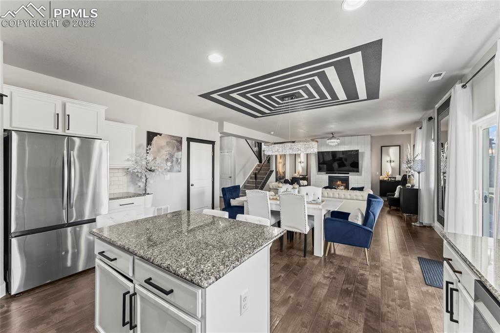 Kitchen with dark stone counters, freestanding refrigerator, white cabinetry, dark wood-type flooring, and recessed lighting