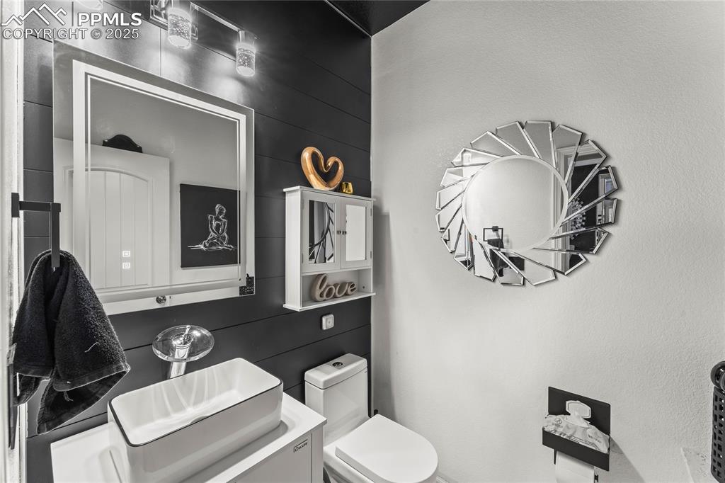 Half bathroom featuring vanity and wood walls