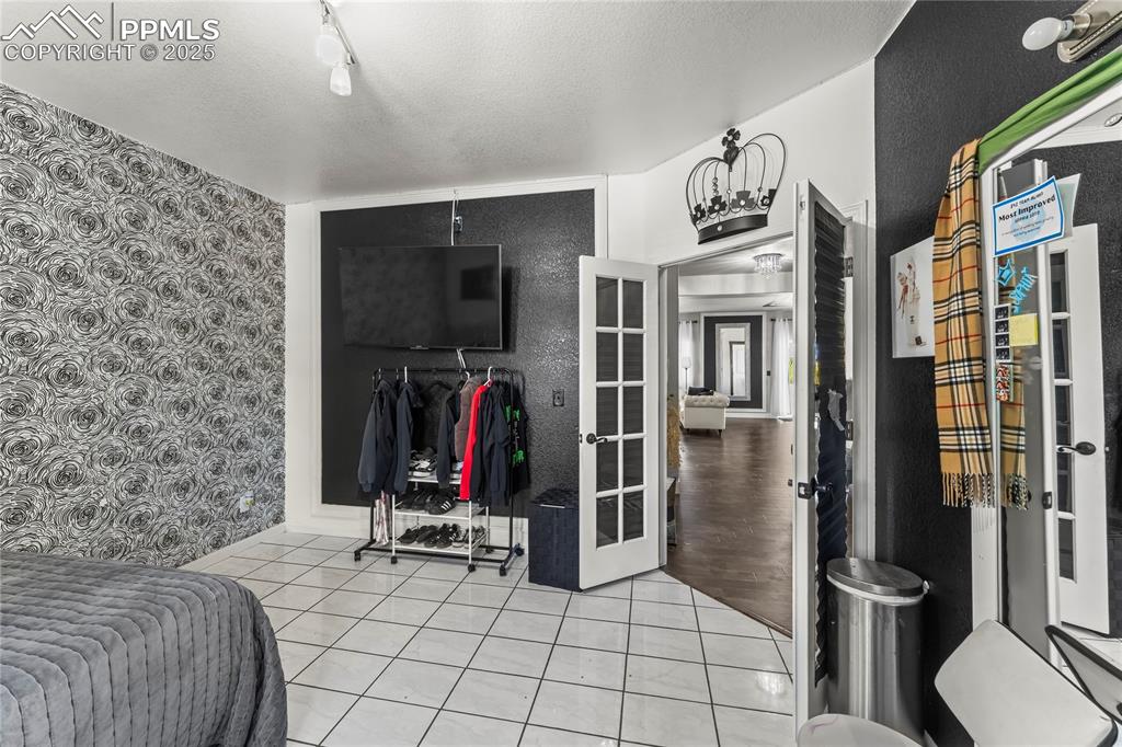 Bedroom with light tile patterned floors, a textured ceiling, wallpapered walls, and track lighting