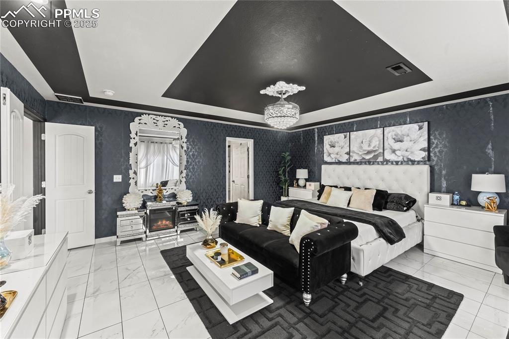 Bedroom with a tray ceiling and wallpapered walls