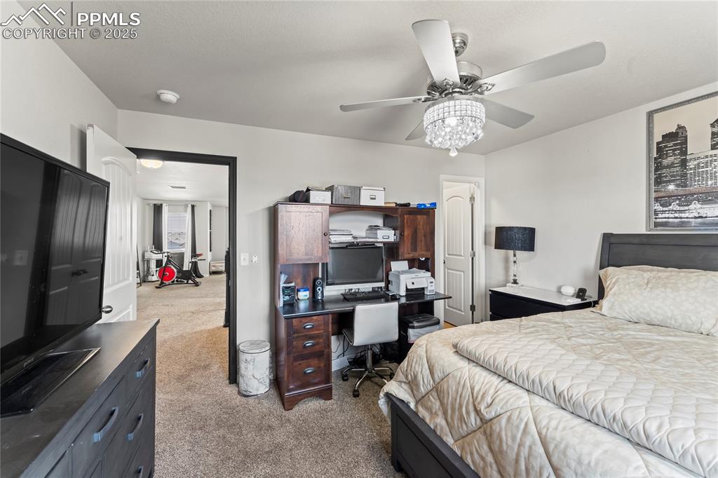 Bedroom with light colored carpet, an office area, and ceiling fan