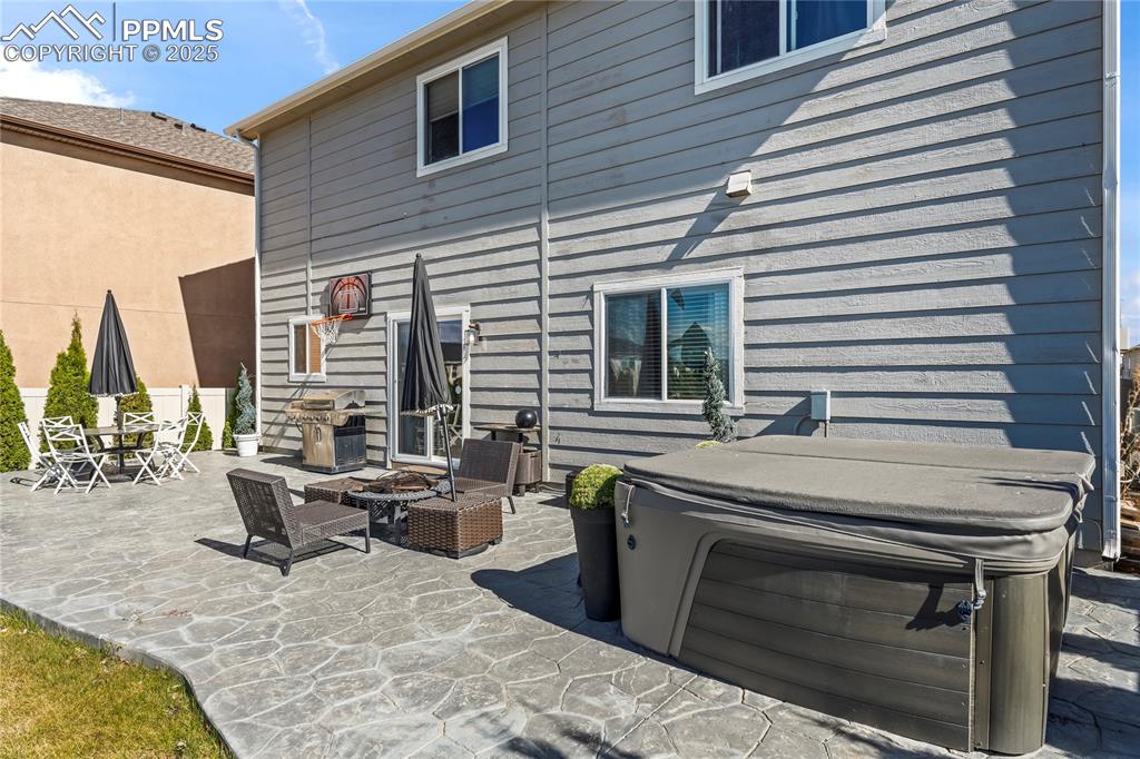 Back of property featuring a hot tub, a patio, and a fire pit