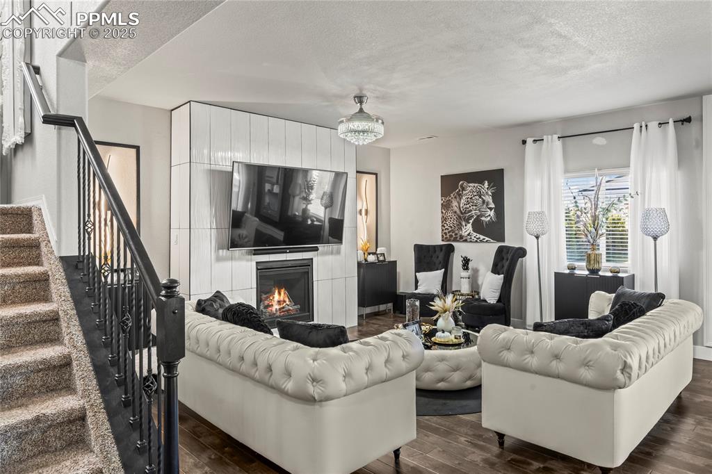 Living area featuring a textured ceiling, dark wood-style floors, stairs, and a fireplace