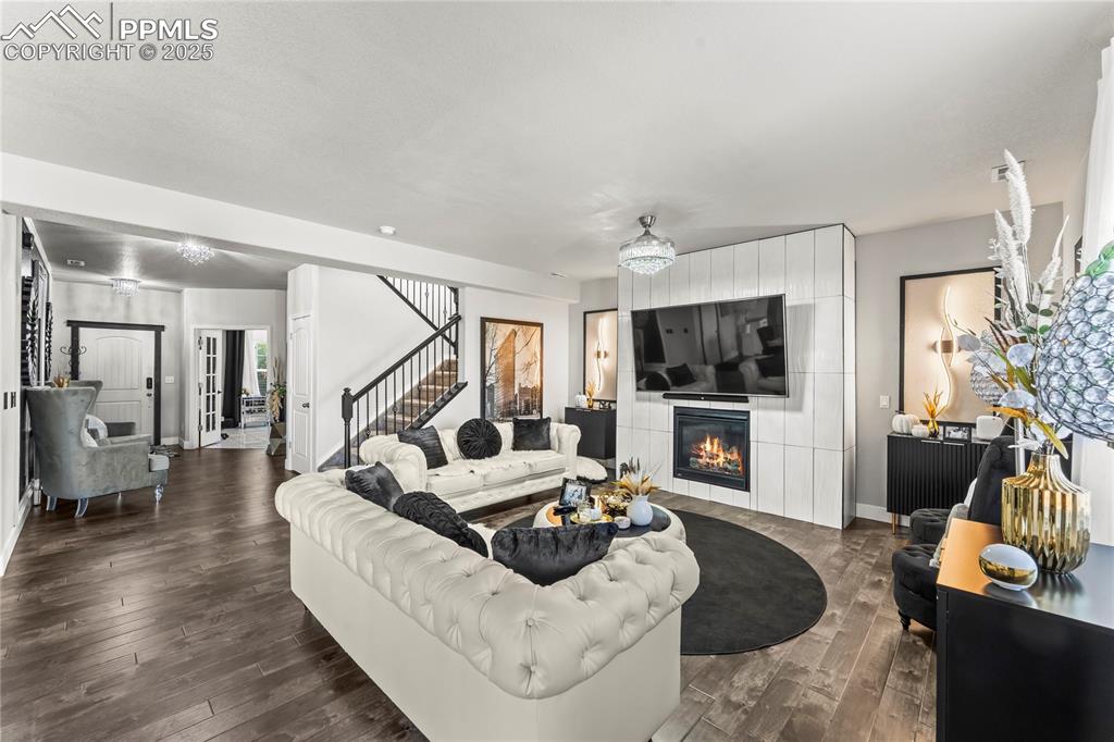 Living area featuring a fireplace, dark wood-style floors, stairway, and a chandelier
