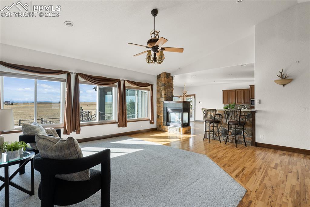 Open-concept living room with triple-sided fireplace, seamless flow to the kitchen, and Front Range views