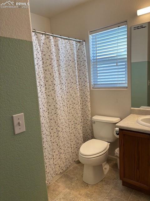 Bathroom with vanity, a textured wall, a shower with shower curtain, and light tile patterned floors
