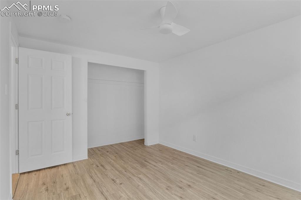 Unfurnished bedroom featuring light wood-style floors, a closet, and ceiling fan