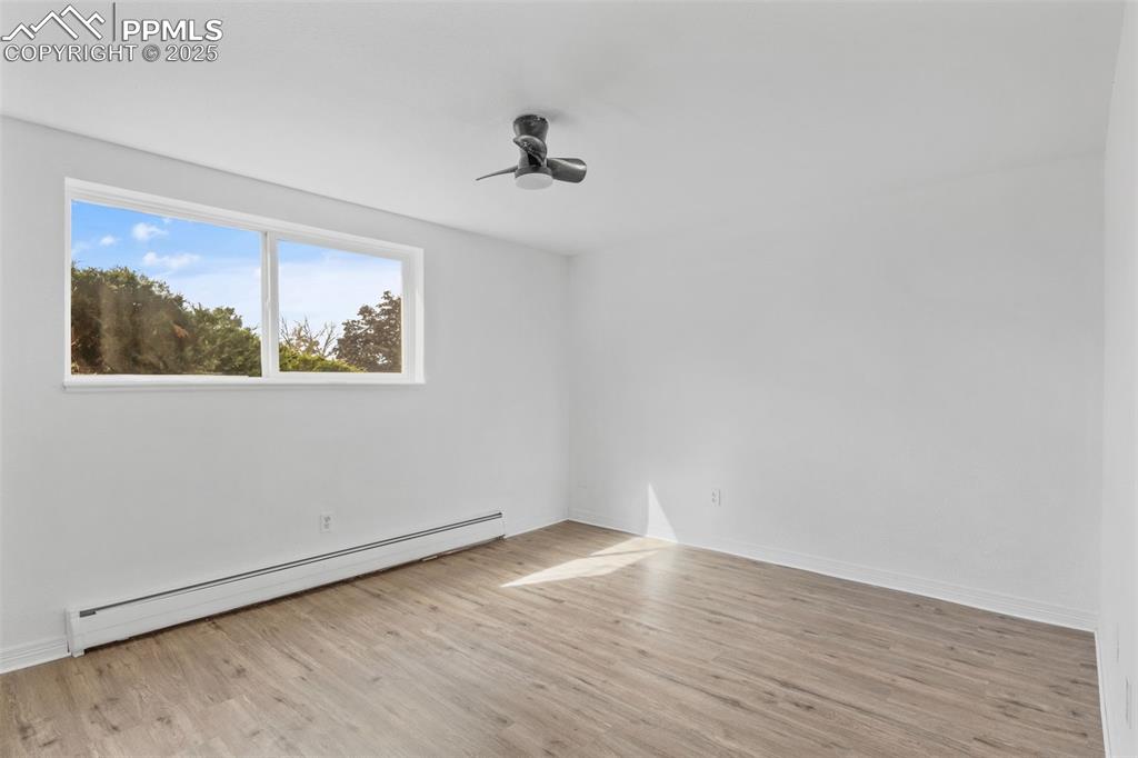 Unfurnished room with baseboard heating and light wood-style floors