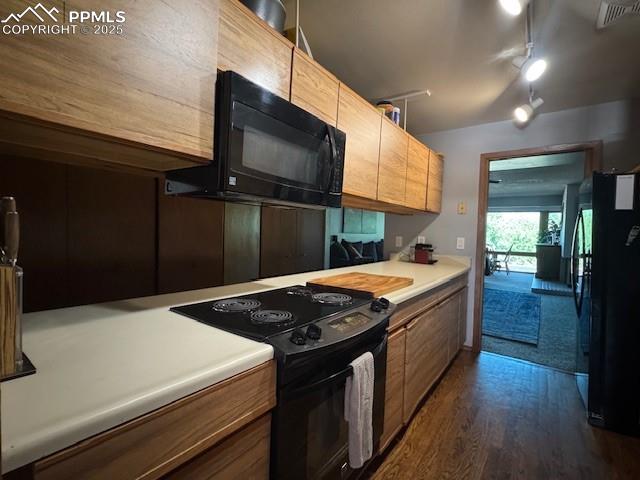 Kitchen featuring black appliances, dark wood-style flooring, light countertops, and rail lighting