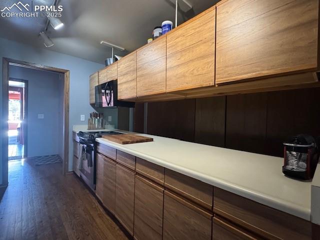 Kitchen with dark wood finished floors, range, light countertops, track lighting, and modern cabinets