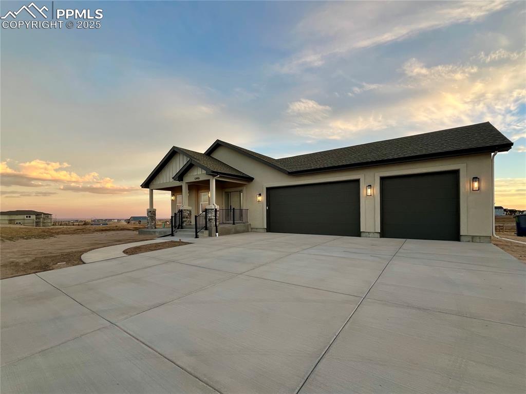 Spacious three-car garage provides ample room for vehicles, storage, and hobbies, with a large concrete parking area for added convenience.