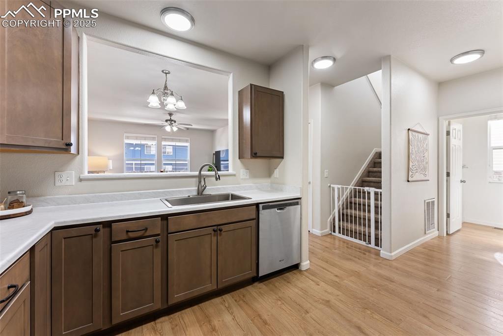 Kitchen featuring light wood finished floors, dishwasher, light countertops, and a chandelier