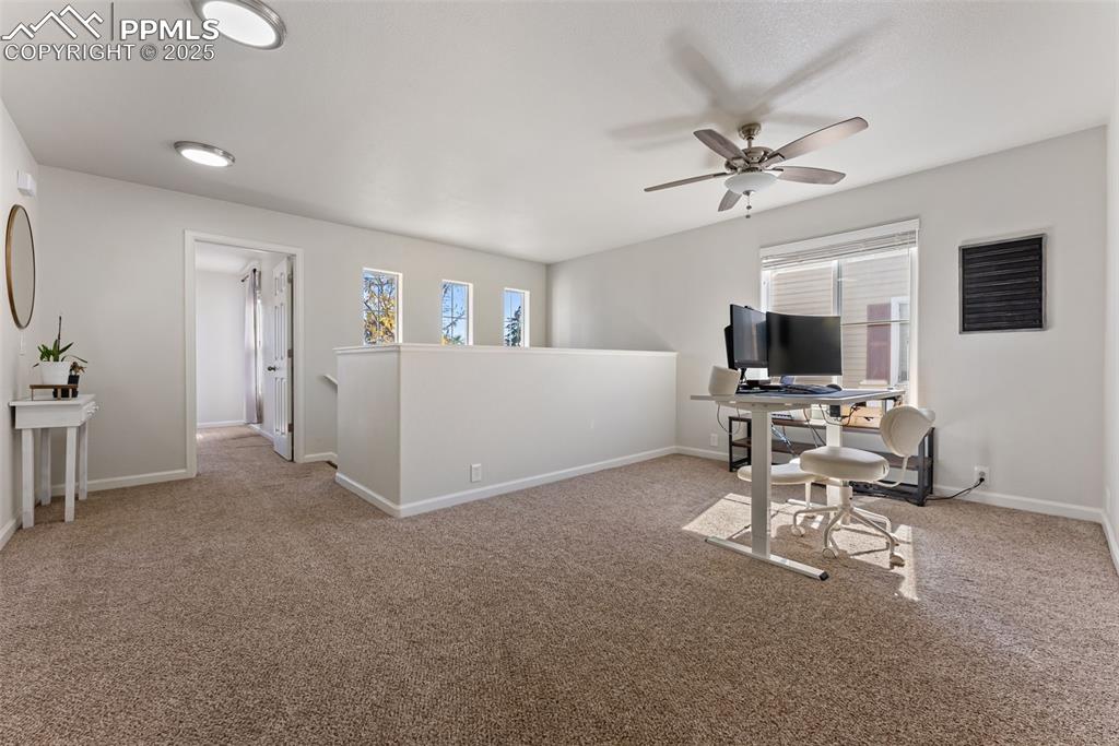 Home office featuring light colored carpet and a ceiling fan