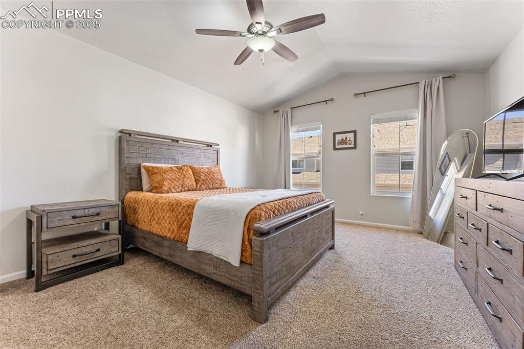 Bedroom featuring light carpet, vaulted ceiling, and ceiling fan