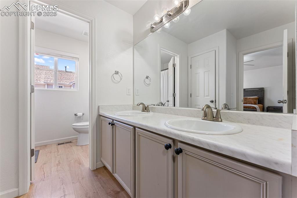 Ensuite bathroom with light wood-style flooring and double vanity