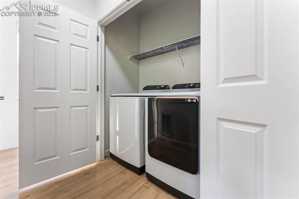 Laundry area with separate washer and dryer and light wood-style floors