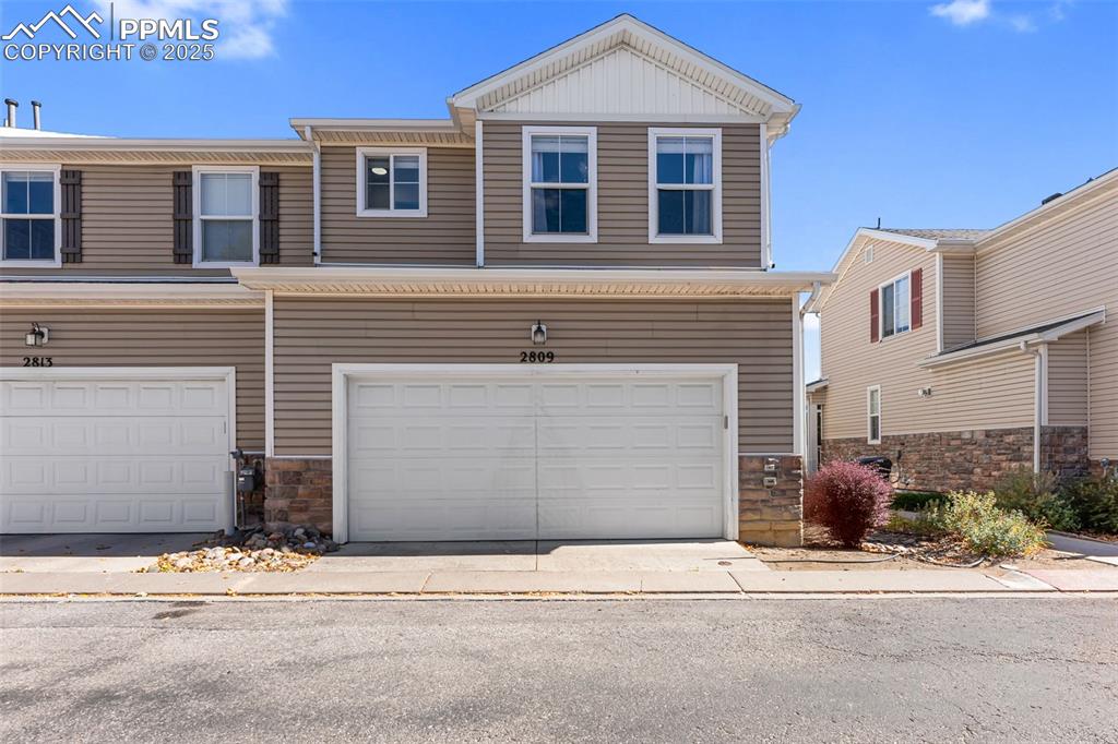View of front of home with stone siding and an attached garage