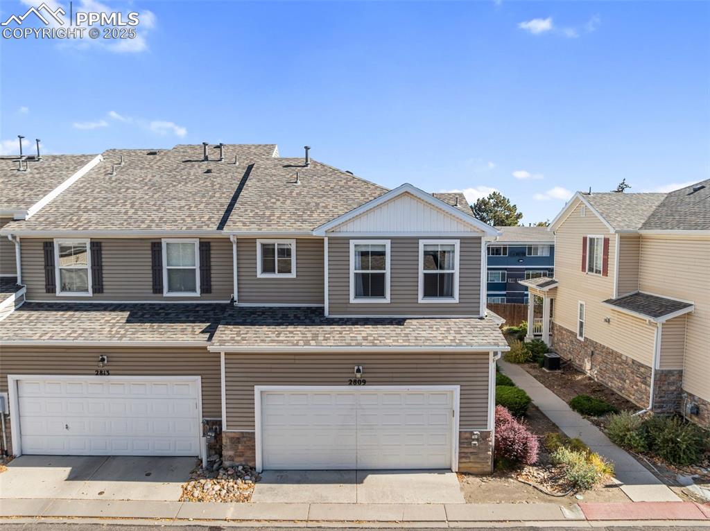 View of front of house with a shingled roof, an attached garage, and concrete driveway