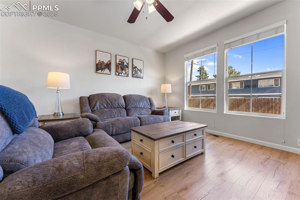 Living room with light wood-type flooring and a ceiling fan