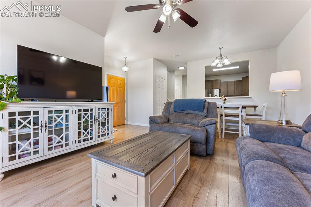 Living room featuring light wood finished floors, a chandelier, and ceiling fan
