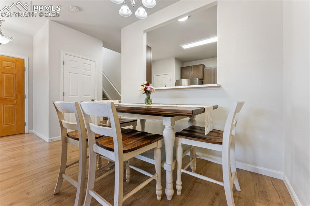 Dining room featuring light wood-style floors, a chandelier, and stairs