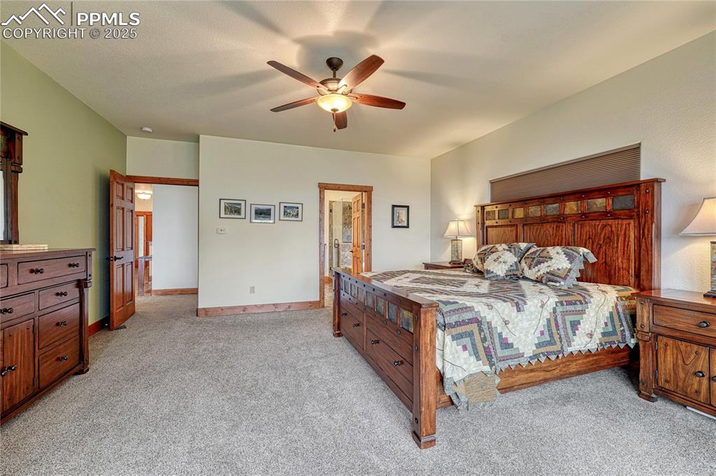 Bedroom with light colored carpet, a ceiling fan, and baseboards