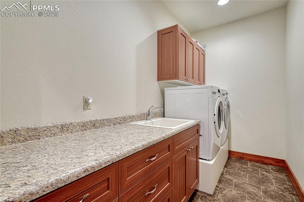 Laundry room with baseboards, washer and clothes dryer, cabinet space, dark stone finish floors, and recessed lighting