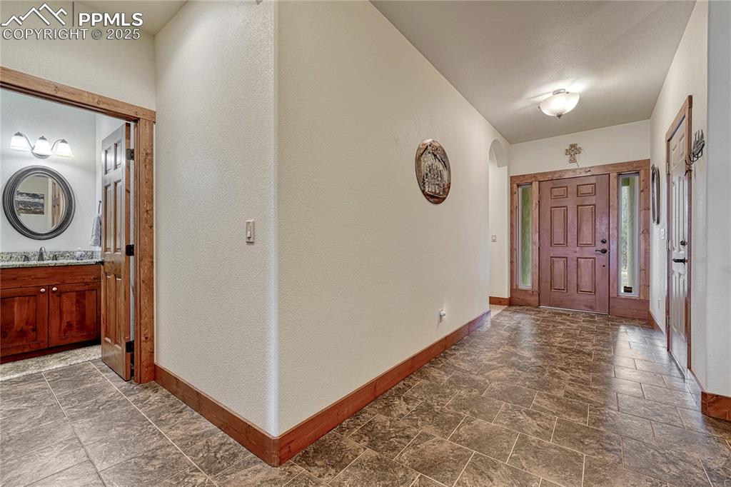Foyer with baseboards, dark stone finish floors, and a textured wall
