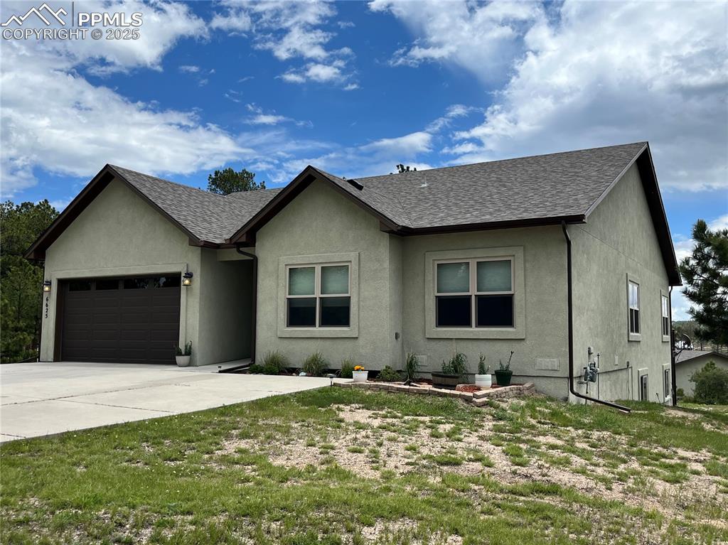 Single story home featuring an attached garage, stucco siding, driveway, and a shingled roof
