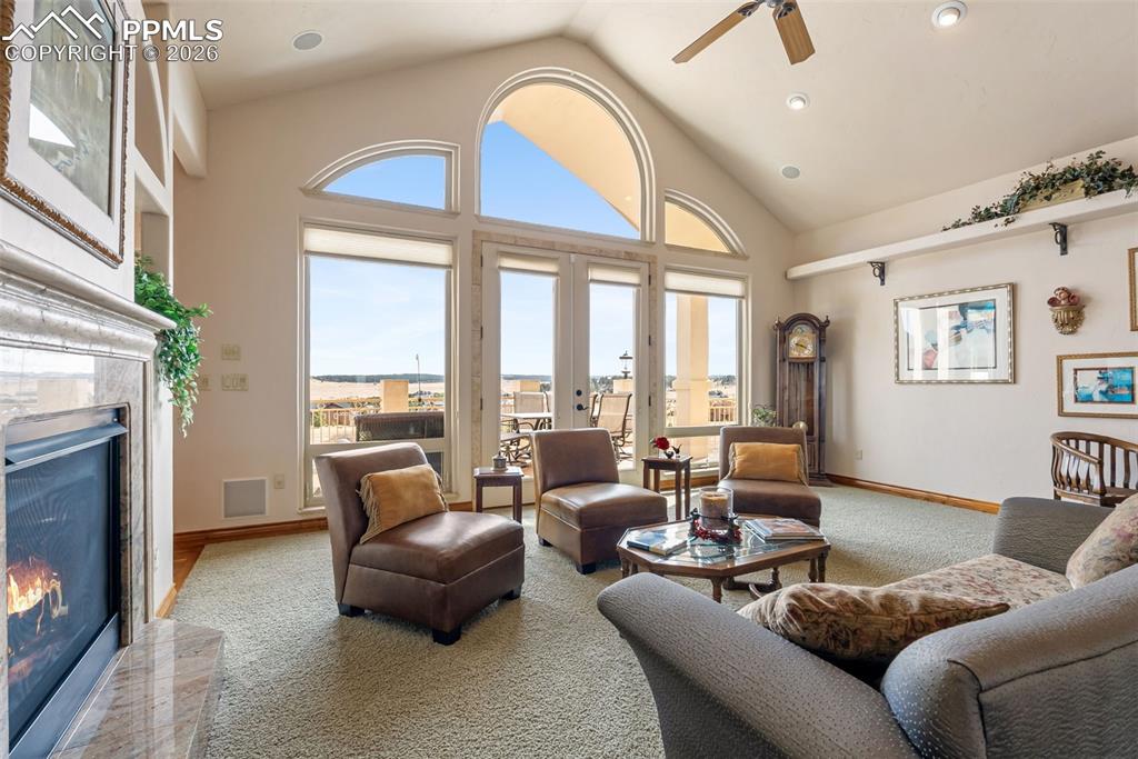 Carpeted living room featuring a fireplace, a ceiling fan, recessed lighting, a high ceiling, and french doors