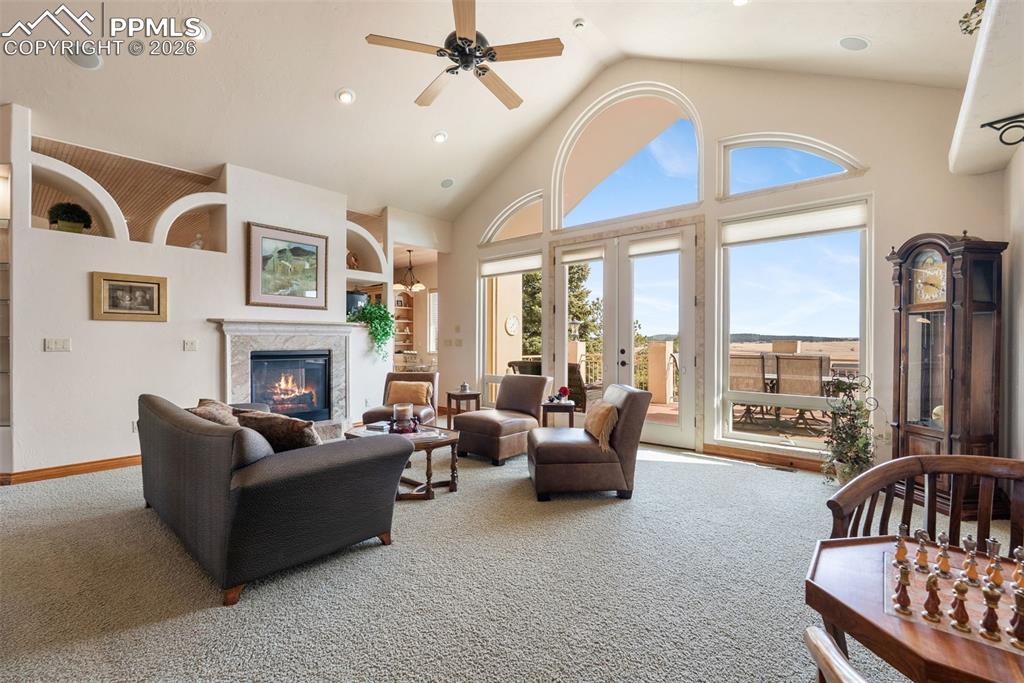 Carpeted living area with built in shelves, recessed lighting, ceiling fan, french doors, and a high ceiling