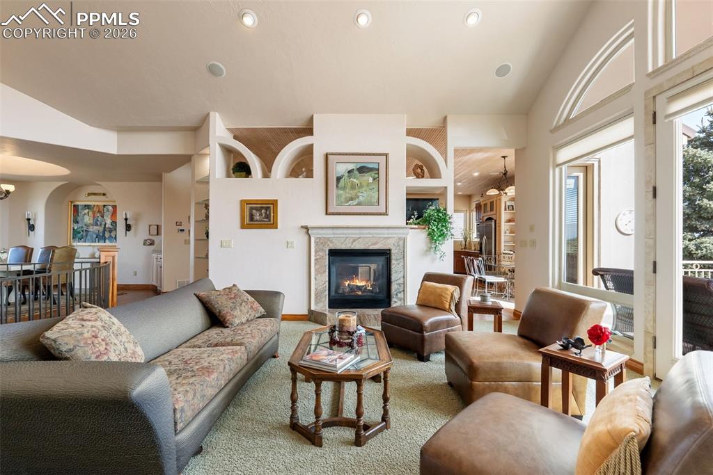 Living room featuring built in features, lofted ceiling, a fireplace, arched walkways, and recessed lighting