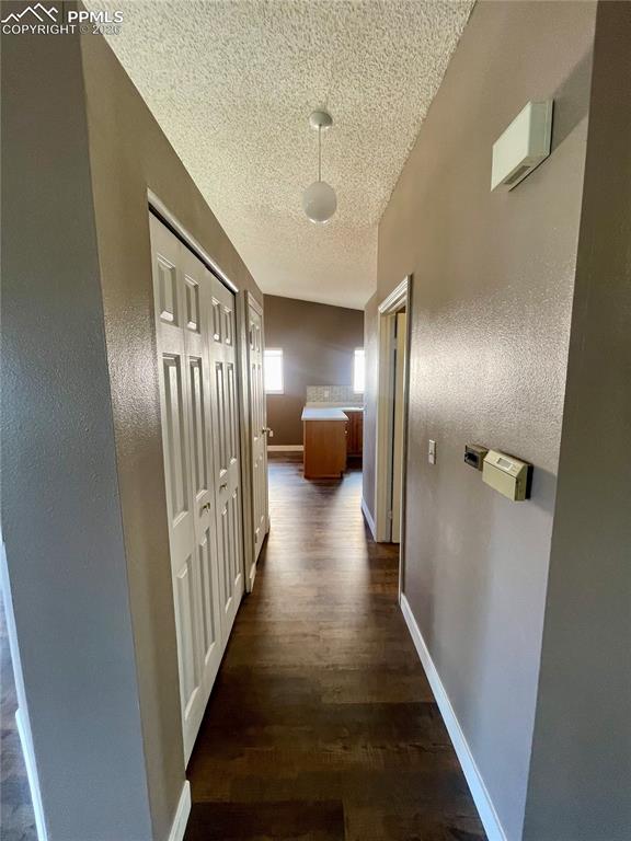 Corridor with dark wood-type flooring and a textured ceiling