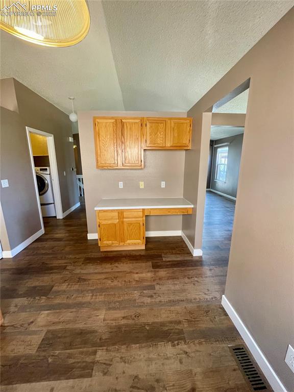 Kitchen featuring light countertops, dark wood-style floors, and washer / clothes dryer